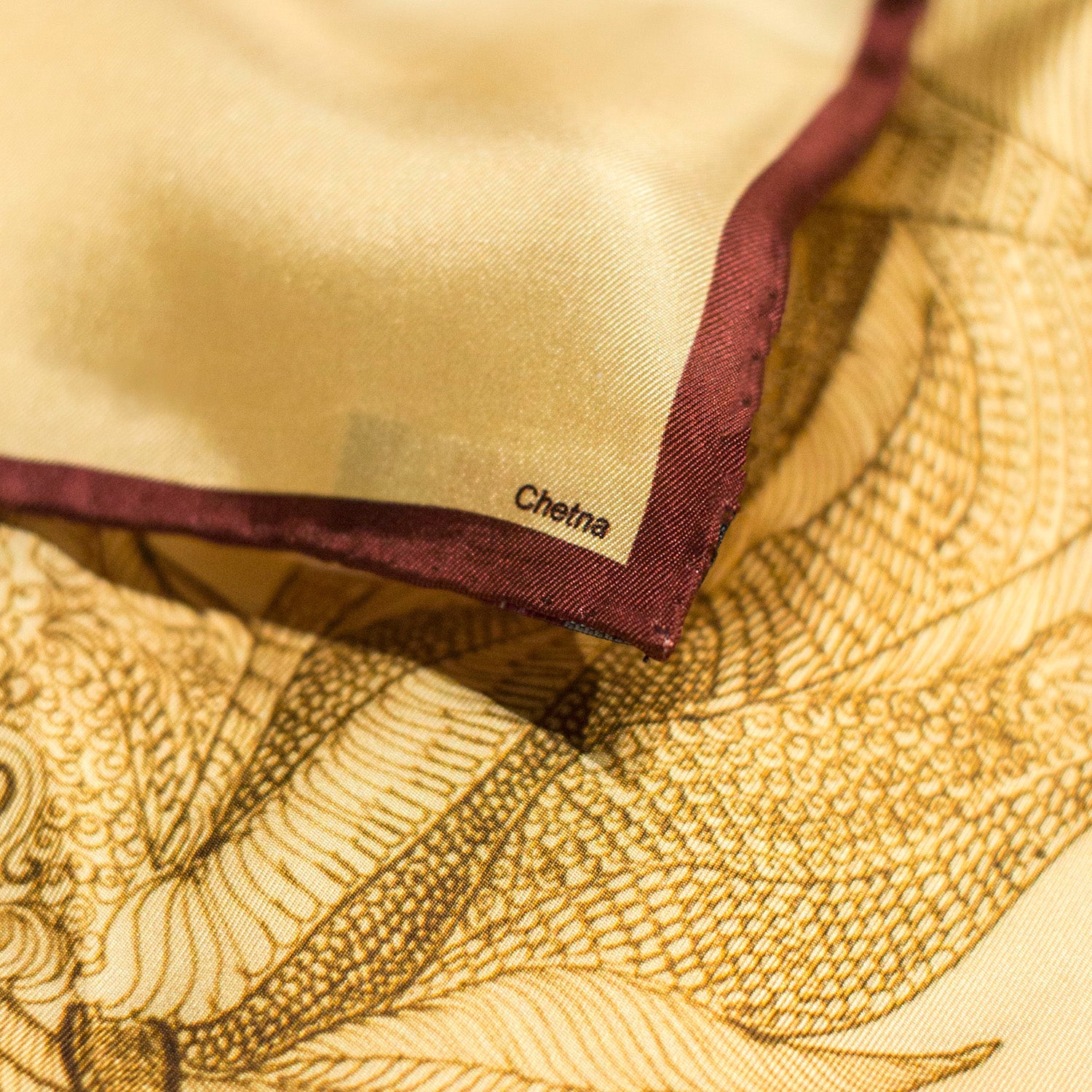 Close-up of Chetna Singh gold tone horse print square silk scarf.