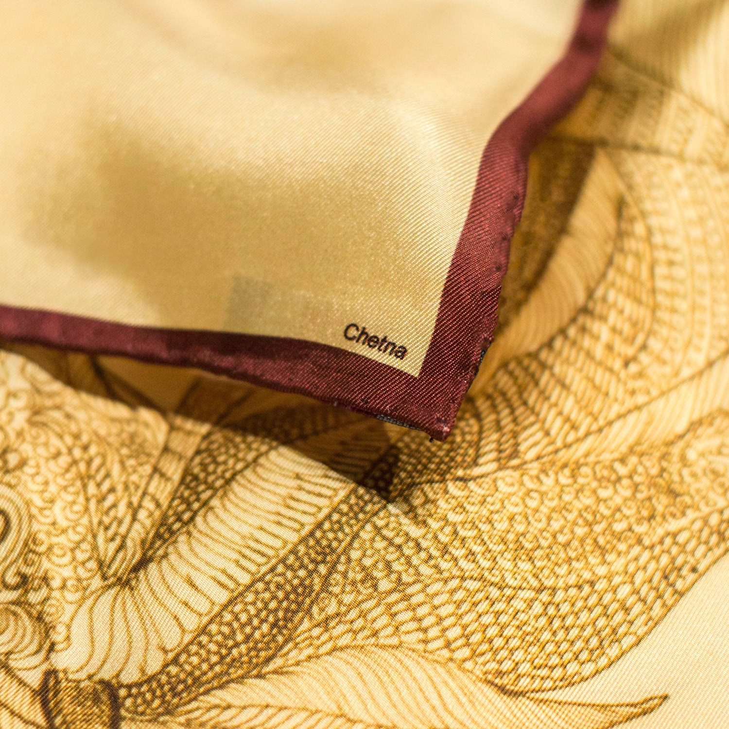 Close-up of Chetna Singh gold tone horse print square silk scarf. 